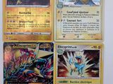 quatre cartes Pokémon posées sur une surface blanche, dont l'une au premier plan