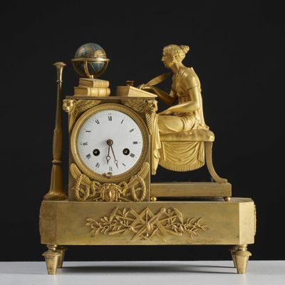 une horloge dorée représentant une femme assise à un bureau
