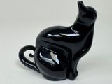 a black cat figurine sitting on a white surface