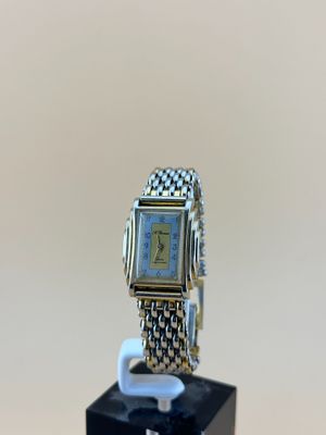 un gros plan d'une montre posée sur un socle noir, sur une table