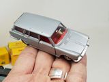 a person holding a silver toy car in their hand