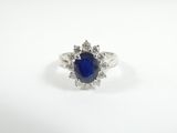 a close up of a blue sapphire and diamond ring on a white surface