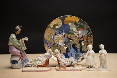 plusieurs figurines représentant des femmes asiatiques et une assiette posées sur une table