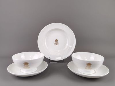 trois assiettes et tasses blanches ornées de bordures dorées sur un fond gris