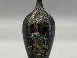 a black vase with a painting on it sitting on a table