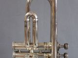 silver plated trumpet on stand against a gray background