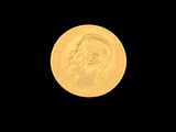 a close up of a gold coin with a face on it