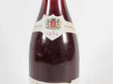 an old bottle of wine sitting on top of a white table