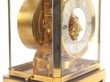 a gold clock with a glass case on a white background