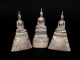 three silver figurines of buddhas sitting on top of each other