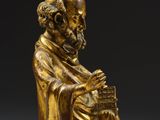 a gold figurine of a man sitting on a chair