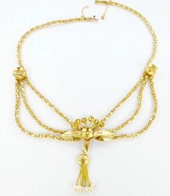 un collier plaqué or orné d'un pompon au bout d'une chaîne