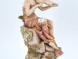 figurine of a man sitting on a rock playing a flute