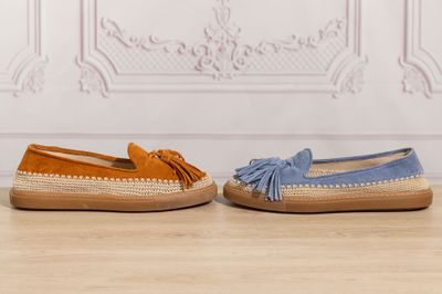 two pairs of blue and orange sued shoes on a wooden floor