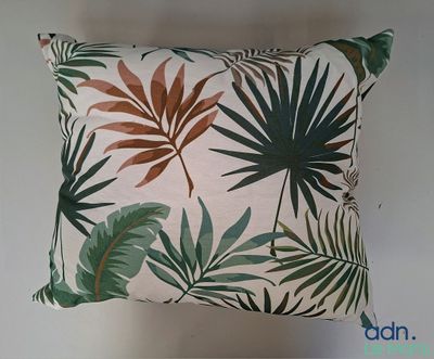 L'oreiller est orné d'un imprimé représentant des feuilles tropicales.