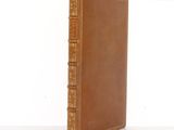 an old book with a brown cover sitting on top of a white table