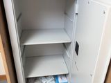 a small white safe box in the corner of a cabinet