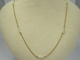 a gold necklace with pearls on a mannequin neck