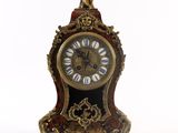 une horloge posée sur un support sur une surface blanche
