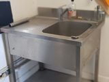 une cuisine avec un évier et un ordinateur portable posé sur le plan de travail