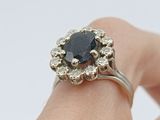 a close up of a person ' s hand holding a ring with a black diamond
