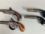 three old guns are displayed on a table with a white background