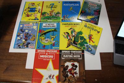 de nombreux livres pour enfants posés sur une table, à côté d'un ordinateur portable