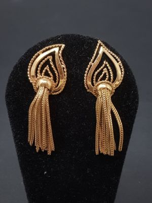 a pair of gold earrings with fringes on a black mannequin