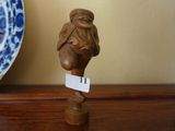 une petite figurine posée sur une table, à côté d'une assiette bleue et blanche