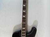 an electric bass guitar hanging on a wall with a white background