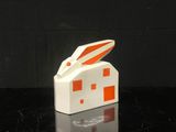 une maison blanche et orange sur le toit de laquelle se trouve un lapin