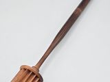 une vieille spatule en bois avec un manche en bois posée sur une surface blanche