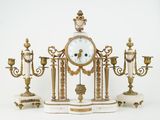 a clock on a stand with three candles and a candle holder