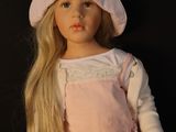 blonde haired doll wearing a pink dress and a pink hat