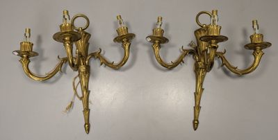 three antique brass wall sconces on a white wall