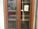 une armoire en bois avec des portes vitrées et un tapis au sol