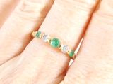an image of a close up of a person ' s hand with a diamond and emerald ring