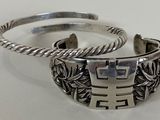 pair of silver cuff bracelets on a white surface with a white background