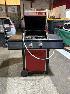 une photo d'un barbecue dans un garage, avec une voiture en arrière-plan