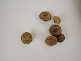 some gold colored buttons are sitting on a white surface