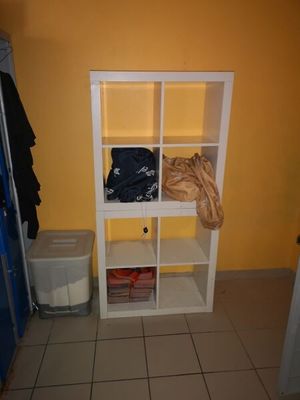 une étagère blanche sur laquelle sont posés des vêtements, dans une pièce jaune