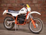 a white and orange dirt bike parked in front of a brick wall