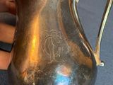 a person holding a silver pitcher on a table