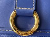 the handle of a blue purse with a gold ring on it