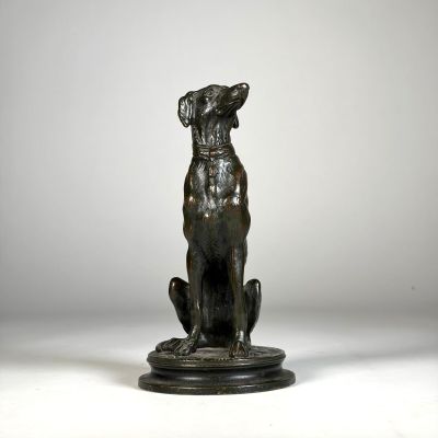 une statue en bronze représentant un chien assis sur un socle