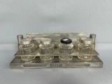 plateau en argent sur lequel sont disposées six flacons de parfum, sur un fond blanc