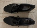 two pairs of black shoes on a tile floor