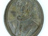 une image représentant une médaille de bronze sur laquelle figure un homme vêtu d'une aube