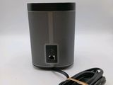 a close up of a speaker on a white surface with a cord