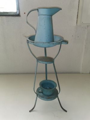 a blue watering pot sitting on a stand on a table